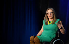 Julie Sawchuk talking to the camera and in her wheelchair on a black background