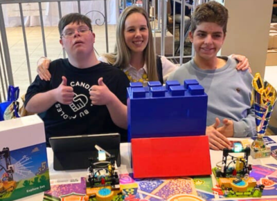 Two boys with LEGO instructor Tara sitting in front of their LEGO masterpieces